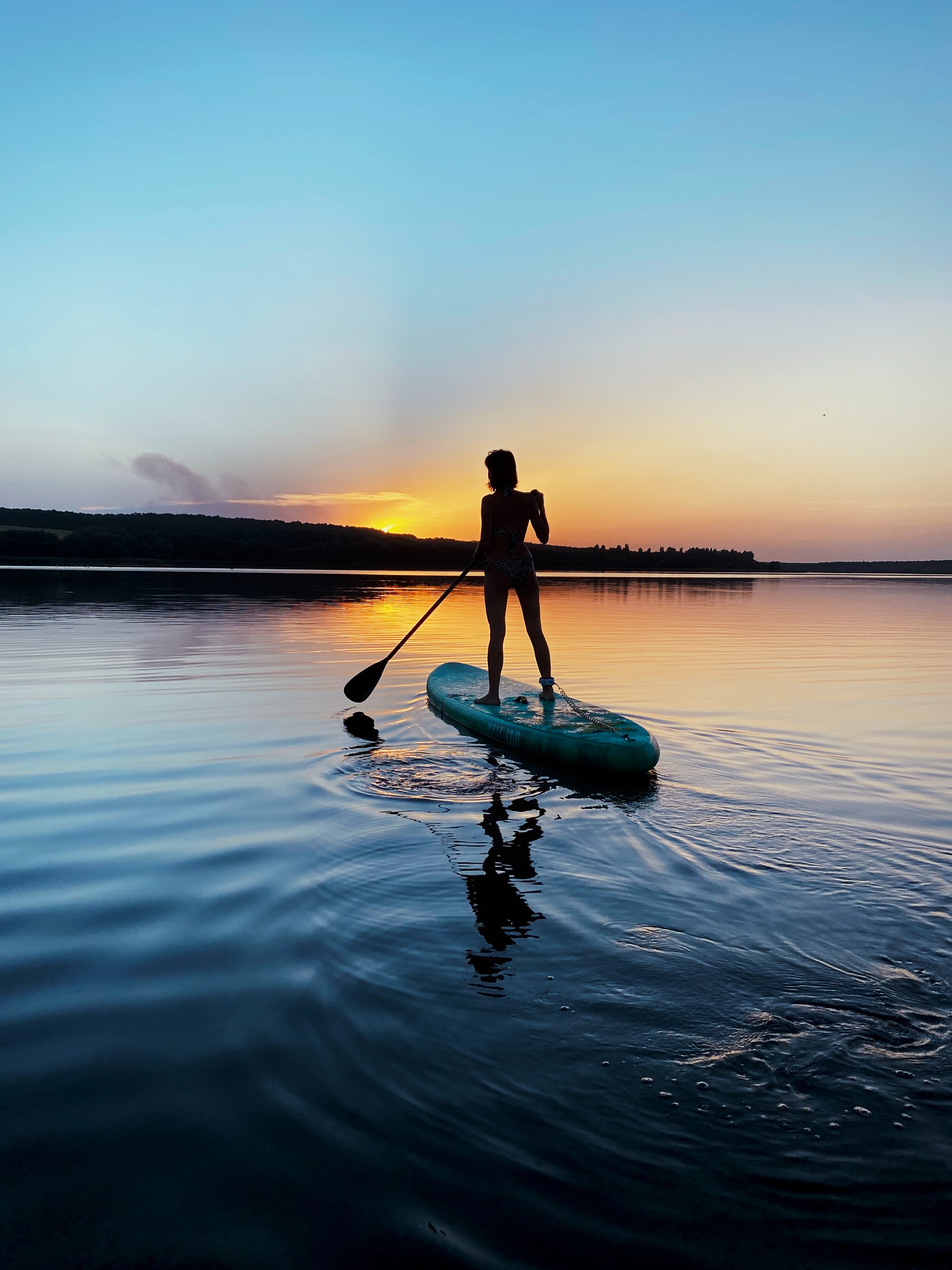 a woman with two dogs on a sup